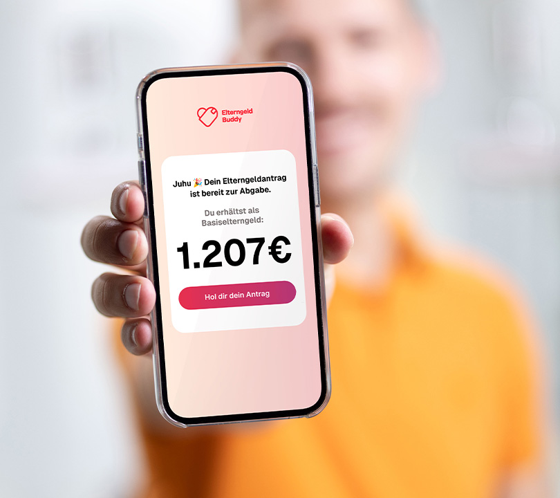 Ingo hält das Smartphone frontal in die Kamera. Die App Elterngeld Buddy ist geöffnet und zeigt den letzten Schritt zum Antrag an.